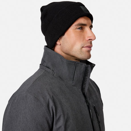 [Model is wearing size M.] A man in profile wearing a black knit beanie and a dark gray technical jacket with a high collar, photographed against a clean light gray studio background.