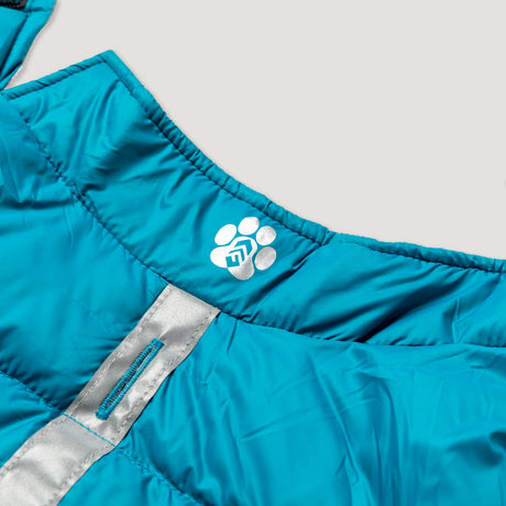 Close-up of the Clearance Dog Down Reversible Mock Jacket in bright blue, featuring padded, water-resistant fabric, a reflective gray strip, and a white paw print logo. Shown on a plain light gray background.