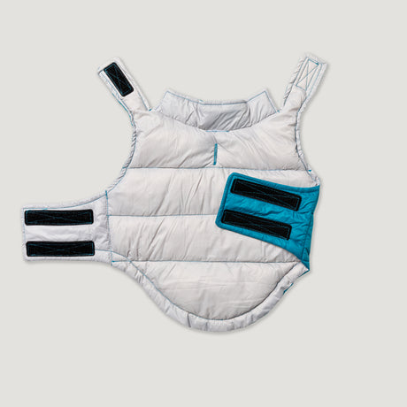 The Clearance Dog Down Reversible Mock Jacket, a padded, sleeveless white and teal piece with black Velcro straps for the chest and shoulders, is shown on a plain light background.