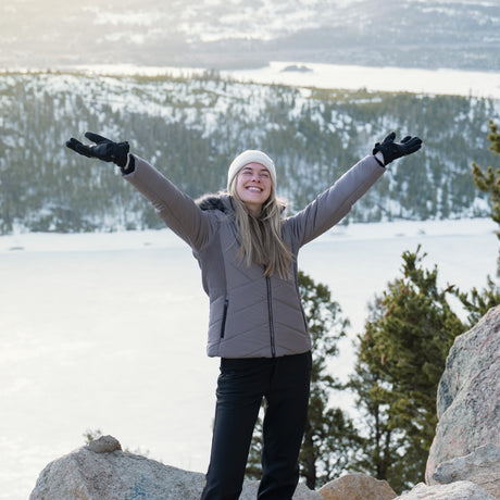 Person in winter clothing with arms outstretched in a snowy landscape