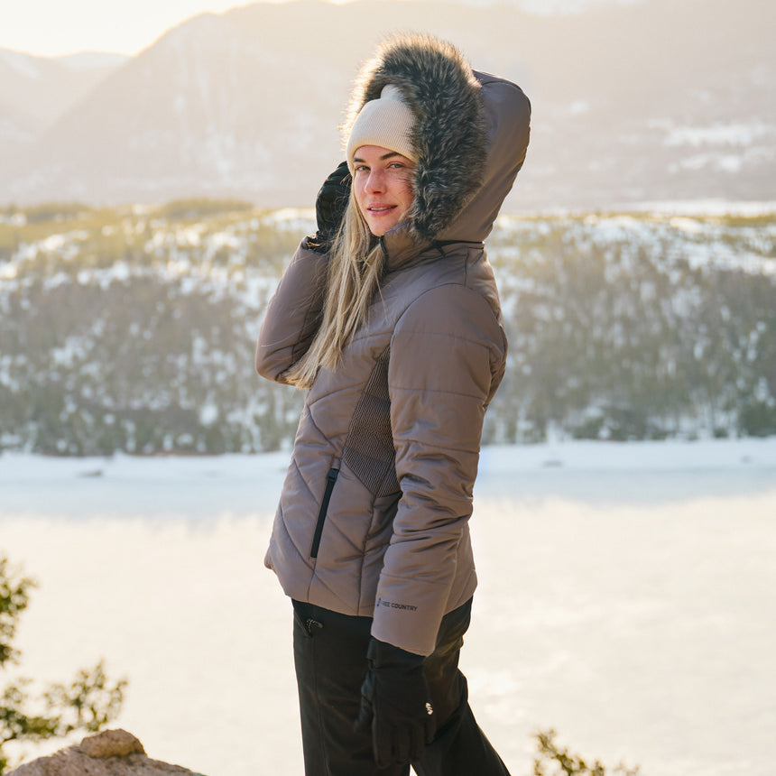 Person wearing a winter coat with fur hood in a snowy landscape
