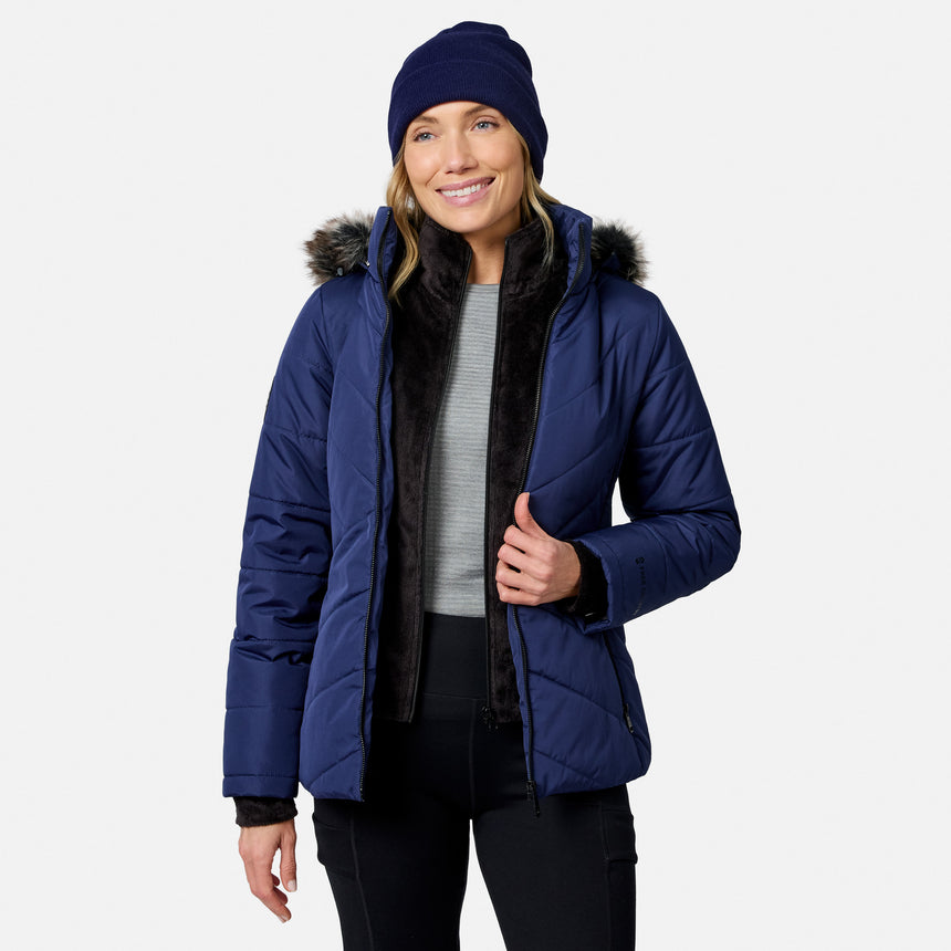A woman wearing a navy blue Women’s Brisk II Parka Jacket with a faux-fur trimmed hood and a matching beanie.