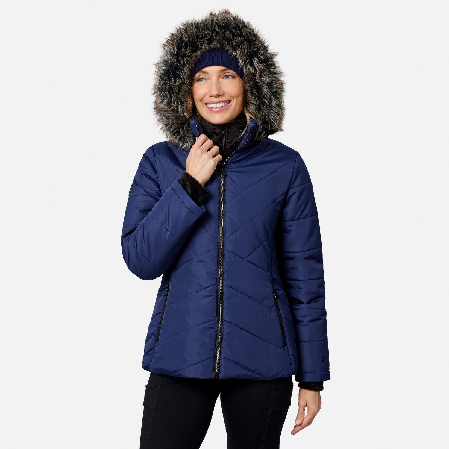 A woman wearing a navy blue quilted Women’s Brisk II Parka Jacket with a faux fur-trimmed hood.