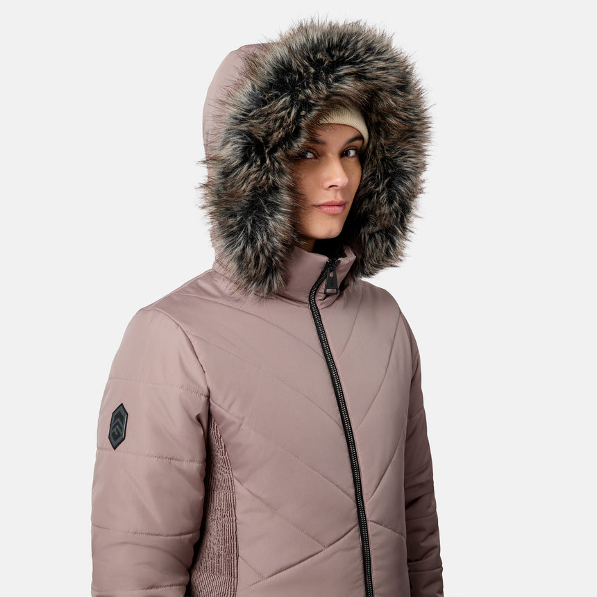Woman wearing a mauve quilted Women’s Brisk II Parka Jacket by Free Country with a faux fur-lined hood.