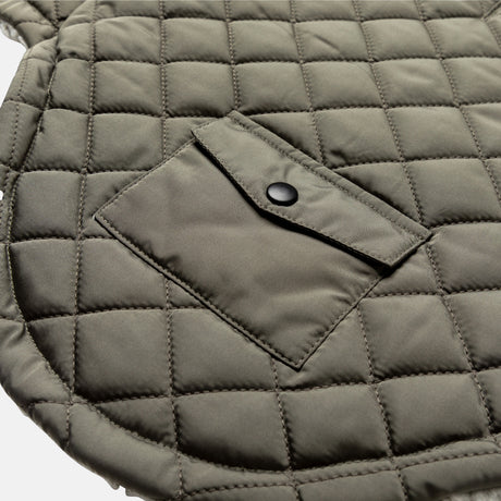 Close-up of the Stratus Lite Reversible Dog Jacket by Clearance, showing olive green quilted fabric with square stitching and a small flap pocket secured with a black snap button.