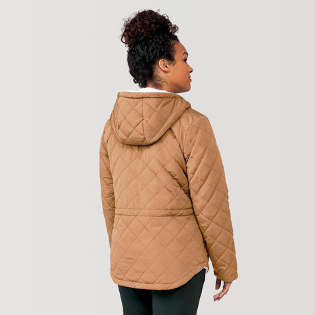 [Alexis is 5’6” wearing a size Small.] Woman wearing Free Country Women's Switch It Up Cloud Lite Reversible Jacket in tan with a full front zipper opening, attached hood with adjustable drawcord, diamond quilting, soft lining, and water resistant and wind resistant stretch performance fabric. light grey background. Perfect women’s  jacket for fall weather.