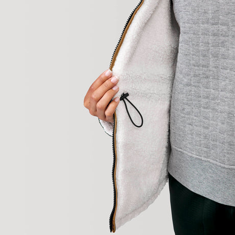 [Alexis is 5’6” wearing a size Small.] Woman wearing Free Country Women's Switch It Up Cloud Lite Reversible Jacket in tan with a full front zipper opening, attached hood with adjustable drawcord, diamond quilting, soft lining, and water resistant and wind resistant stretch performance fabric. light grey background. Perfect women’s  jacket for fall weather.
