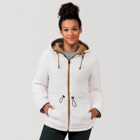 [Alexis is 5’6” wearing a size Small.] Woman wearing Free Country Women's Switch It Up Cloud Lite Reversible Jacket in tan with a full front zipper opening, attached hood with adjustable drawcord, diamond quilting, soft lining, and water resistant and wind resistant stretch performance fabric. light grey background. Perfect women’s  jacket for fall weather.