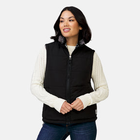 [Megan is 5’6” wearing a size Small.] Woman wearing the Free Country Women's Venture Stratus Lite Reversible Vest in black, featuring a geometric-print Butter Pile® lining and horizontal quilted overlay