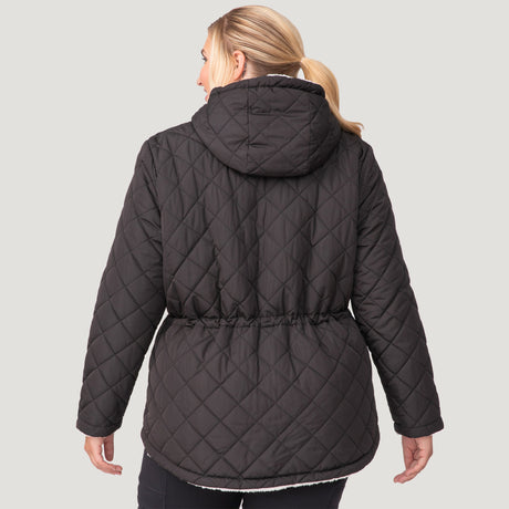 [Lola is 5'10.5" wearing a size 1X.] Woman wearing Free Country Women's Plus Size Switch It Up Cloud Lite Reversible Jacket in black with a full front zipper opening, attached hood with adjustable drawcord, diamond quilting, soft lining, and water resistant and wind resistant stretch performance fabric. light grey background. Perfect women’s  jacket for fall weather.