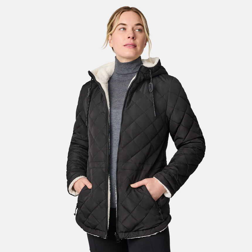 [CJ is 5'10" wearing size S.] Woman wearing Free Country Women's Switch It Up Cloud Lite Reversible Jacket in black with a full front zipper opening, attached hood with adjustable drawcord, diamond quilting, soft lining, and water resistant and wind resistant stretch performance fabric. light grey background. Perfect women’s  jacket for fall weather.