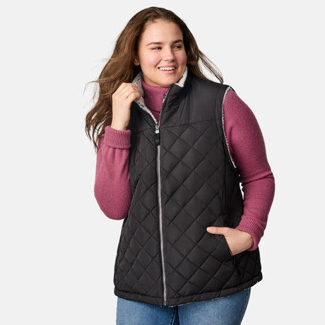 [Karissa is 5'9.5" wearing size 1X.]  Women’s Free Country black diamond-quilted vest with zip-front closure—reverses to cozy sherpa for added warmth and texture. Worn open over a pink knit sweater and blue jeans for a relaxed, cold-weather look.