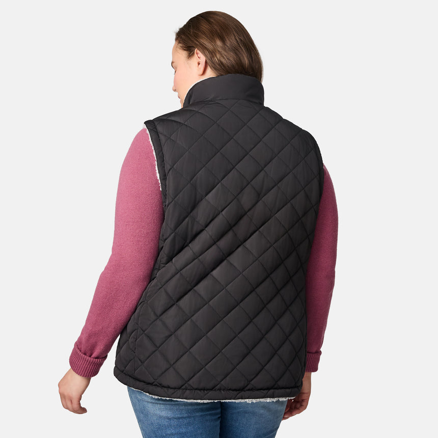 [Karissa is 5'9.5" wearing size 1X.]  Women’s Free Country black diamond-quilted vest with zip-front closure—reverses to cozy sherpa for added warmth and texture. Worn open over a pink knit sweater and blue jeans for a relaxed, cold-weather look.