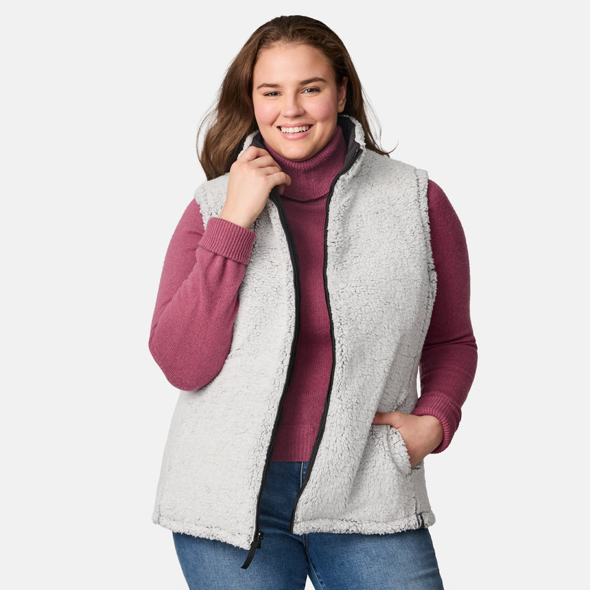 [Karissa is 5'9.5" wearing size 1X.]  Women’s Free Country black diamond-quilted vest with zip-front closure—reverses to cozy sherpa for added warmth and texture. Worn open over a pink knit sweater and blue jeans for a relaxed, cold-weather look.