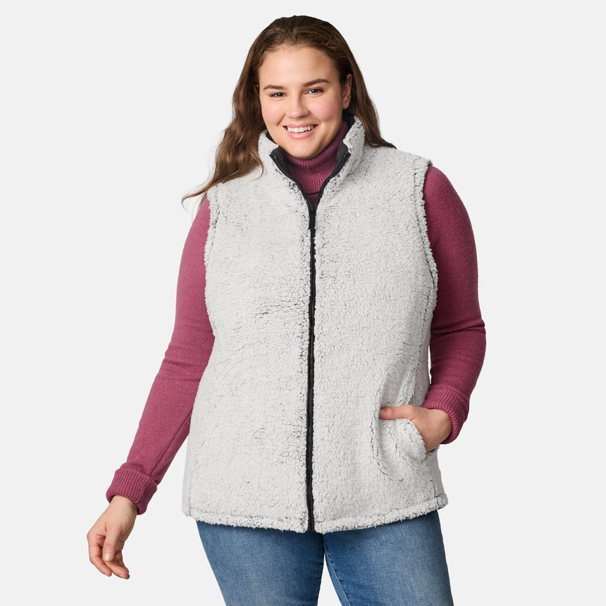 [Karissa is 5'9.5" wearing size 1X.]  Women’s Free Country black diamond-quilted vest with zip-front closure—reverses to cozy sherpa for added warmth and texture. Worn open over a pink knit sweater and blue jeans for a relaxed, cold-weather look.