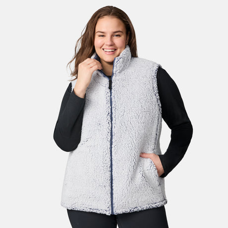 [Karissa is 5'9.5" wearing size 1X.] Women’s Free Country blue quilted vest with zip-front closure and zippered pockets—reverses to cozy sherpa for added warmth and texture. Worn over a black long-sleeve shirt and blue pants for a casual, transitional-weather look.