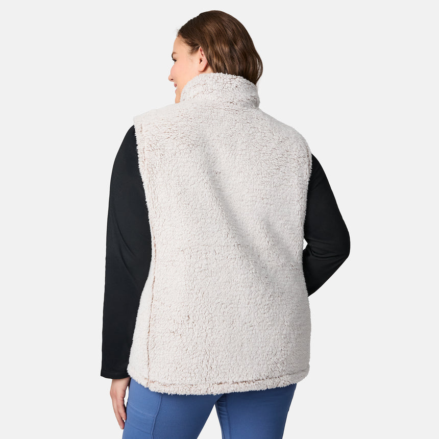 [Karissa is 5'9.5" wearing size 1X.] Women’s Free Country light beige quilted vest with zip-front closure and zippered pockets—reverses to cozy sherpa for added warmth and texture. Worn over a black long-sleeve shirt and blue pants for a casual, transitional-weather look.