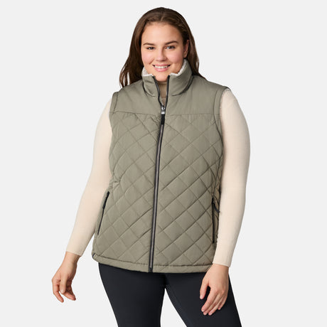 [Karissa is 5'9.5" wearing size 1X.]  Women’s Free Country light green diamond-quilted vest with zip-front closure and zippered pockets—reverses to cozy sherpa for added warmth and texture. Styled over a light long-sleeve shirt and dark pants for a versatile, cold-weather look.