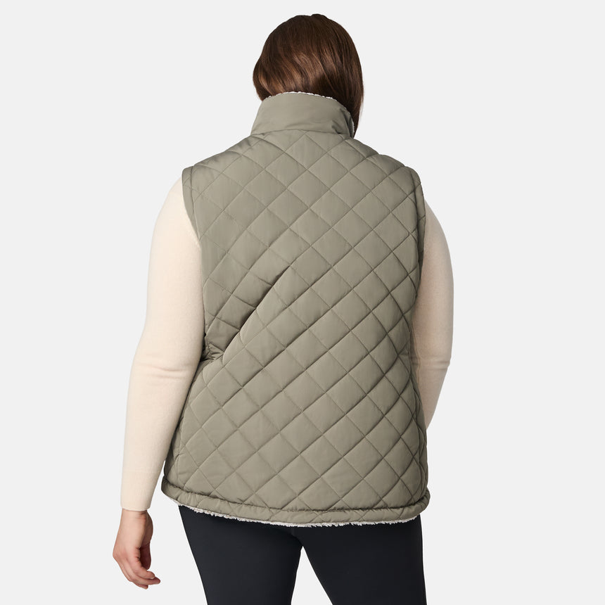 [Karissa is 5'9.5" wearing size 1X.]  Women’s Free Country light green diamond-quilted vest with zip-front closure and zippered pockets—reverses to cozy sherpa for added warmth and texture. Styled over a light long-sleeve shirt and dark pants for a versatile, cold-weather look.