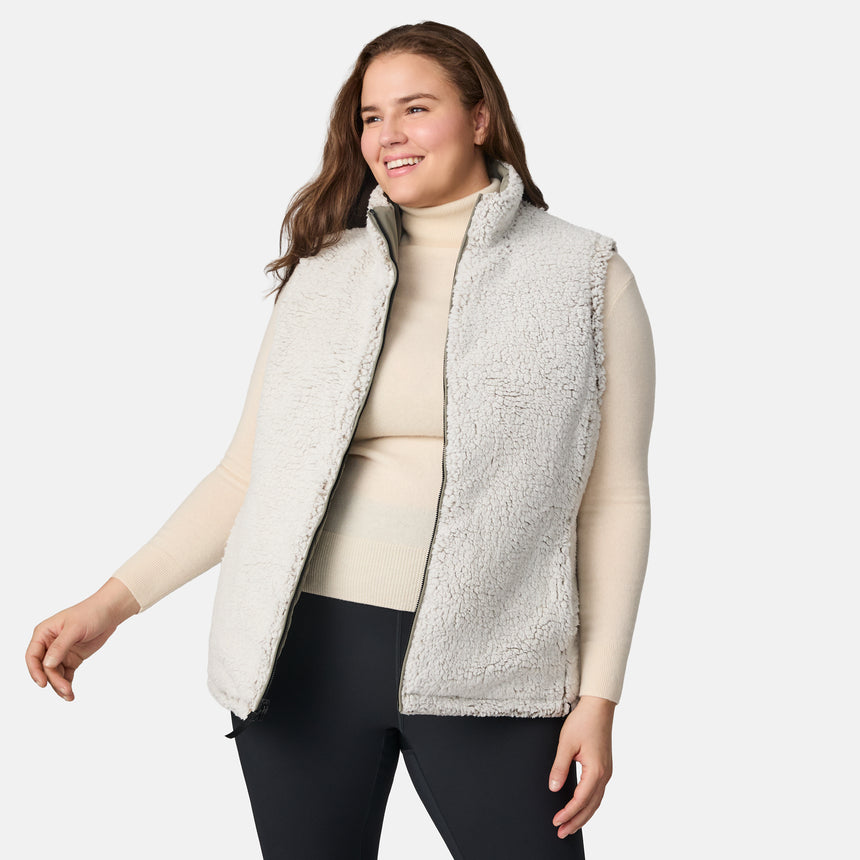 [Karissa is 5'9.5" wearing size 1X.]  Women’s Free Country light green diamond-quilted vest with zip-front closure and zippered pockets—reverses to cozy sherpa for added warmth and texture. Styled over a light long-sleeve shirt and dark pants for a versatile, cold-weather look.