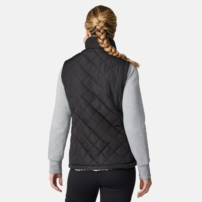 [CJ is 5'10" wearing size S.] Women’s Free Country black quilted vest with zip-front closure and dual zippered pockets—reversible to cozy sherpa for added warmth and versatile styling. Layered over a light gray long-sleeve shirt for a casual, cold-weather look.