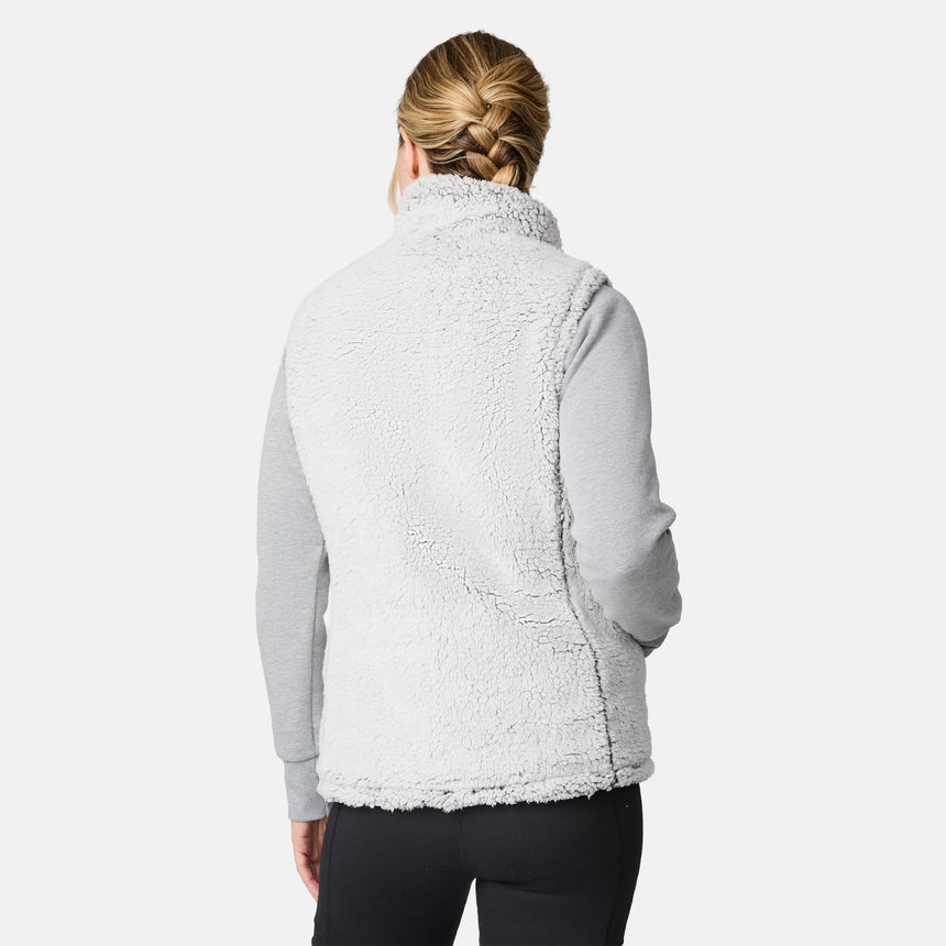 [CJ is 5'10" wearing size S.] Women’s Free Country black quilted vest with zip-front closure and dual zippered pockets—reversible to cozy sherpa for added warmth and versatile styling. Layered over a light gray long-sleeve shirt for a casual, cold-weather look.