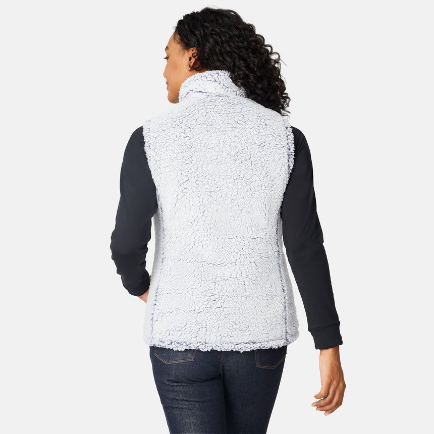 [Angelique is 5'10" wearing size S.] Women’s Free Country blue diamond-quilted vest with zip-front closure—reverses to cozy sherpa for added warmth and texture. Styled over a black long-sleeve shirt with one hand in pocket, set against a clean white background.
