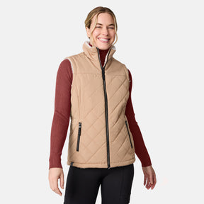 [CJ is 5'10" wearing size S.] Women’s Free Country beige diamond-quilted vest with zippered pockets and high collar—reverses to cozy sherpa for added warmth and texture. Layered over a green ribbed sweater and black pants for a stylish, cold-weather look.
