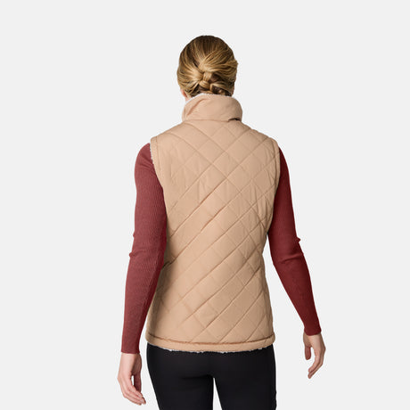 [CJ is 5'10" wearing size S.] Women’s Free Country beige diamond-quilted vest with zippered pockets and high collar—reverses to cozy sherpa for added warmth and texture. Layered over a green ribbed sweater and black pants for a stylish, cold-weather look.