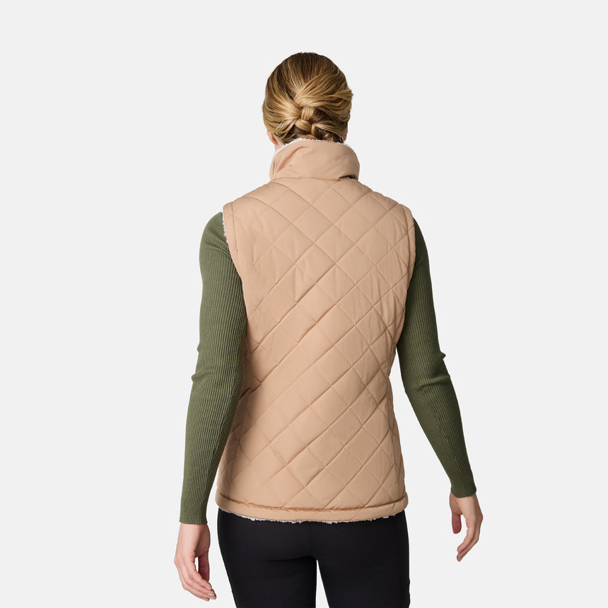 [CJ is 5'10" wearing size S.] Women’s Free Country beige diamond-quilted vest with zippered pockets and high collar—reverses to cozy sherpa for added warmth and texture. Layered over a green ribbed sweater and black pants for a stylish, cold-weather look.