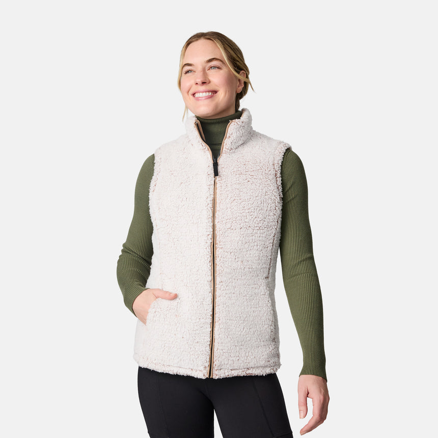[CJ is 5'10" wearing size S.] Women’s Free Country beige diamond-quilted vest with zippered pockets and high collar—reverses to cozy sherpa for added warmth and texture. Layered over a green ribbed sweater and black pants for a stylish, cold-weather look.