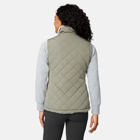 [Angelique is 5'10" wearing size S.] Women’s Free Country light green quilted vest with diamond pattern and black zippered pockets—reverses to cozy sherpa for added warmth and texture. Styled over a gray long-sleeve shirt and blue pants for a relaxed, transitional-weather look.