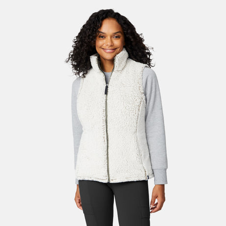 [Angelique is 5'10" wearing size S.] Women’s Free Country light green quilted vest with diamond pattern and black zippered pockets—reverses to cozy sherpa for added warmth and texture. Styled over a gray long-sleeve shirt and blue pants for a relaxed, transitional-weather look.