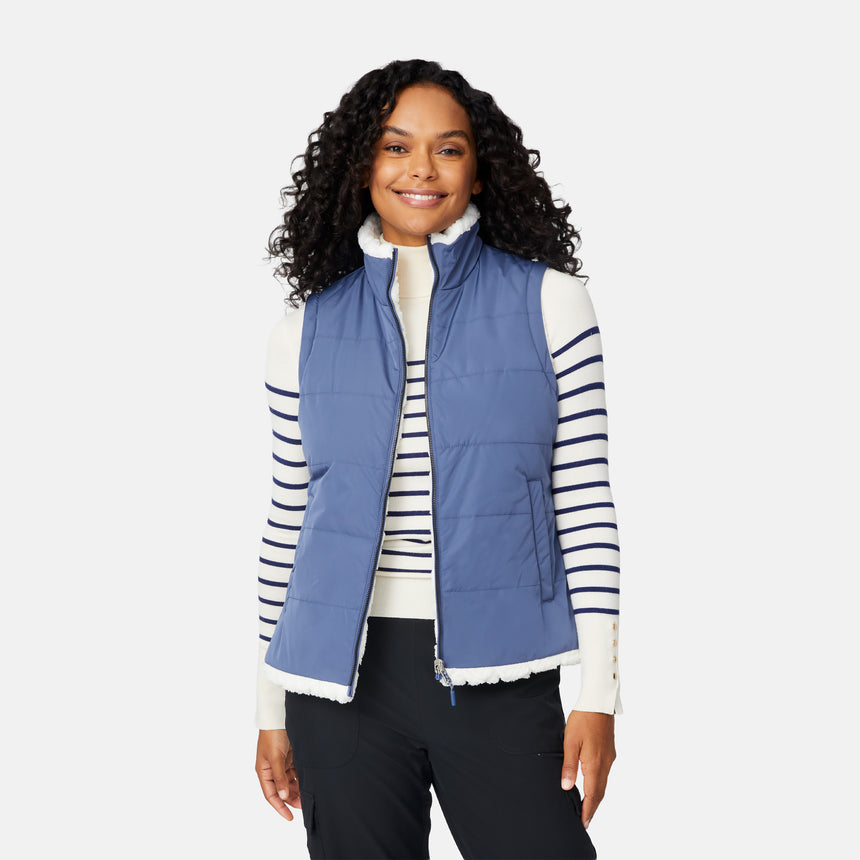 [Angelique is 5'10" wearing size S.] Woman wearing a blue puffer vest over a striped shirt on a white background