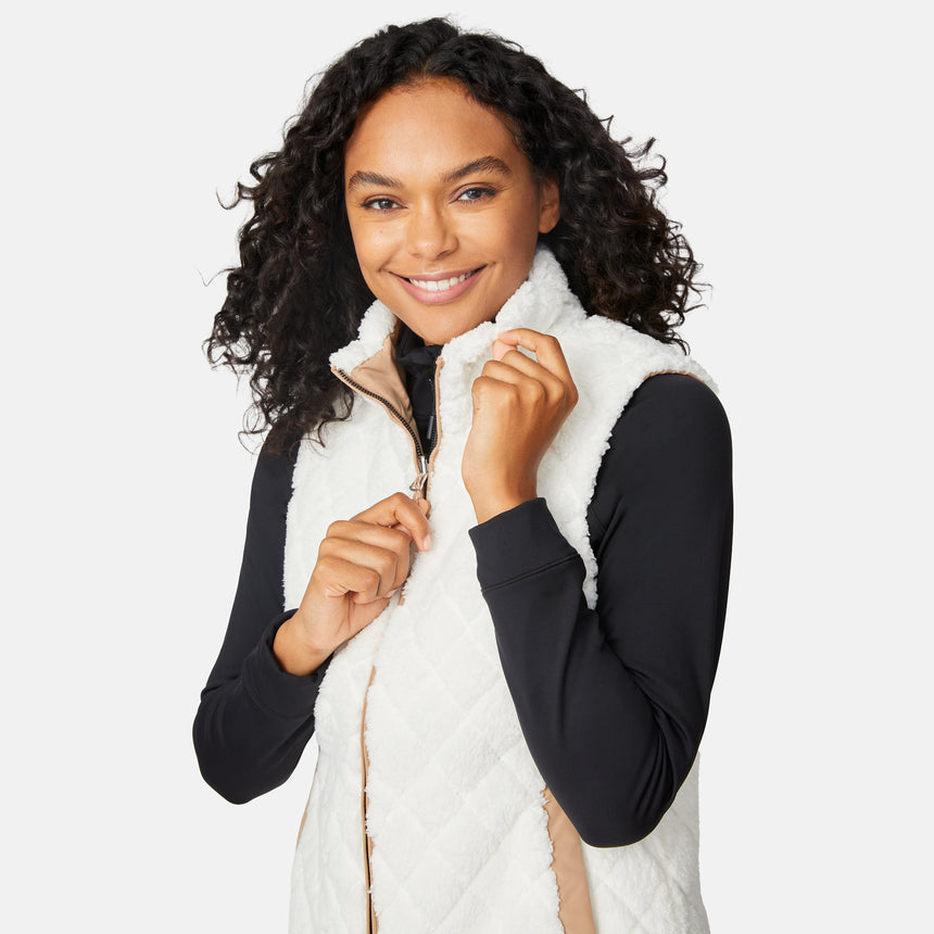 [Angelique is 5'10" wearing size S.] Woman wearing a white puffer vest over a black long-sleeve shirt on a light gray background