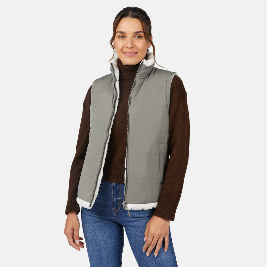 [Olga is 5'9" wearing size S.] Woman wearing a green puffer vest over a brown sweater on a white background