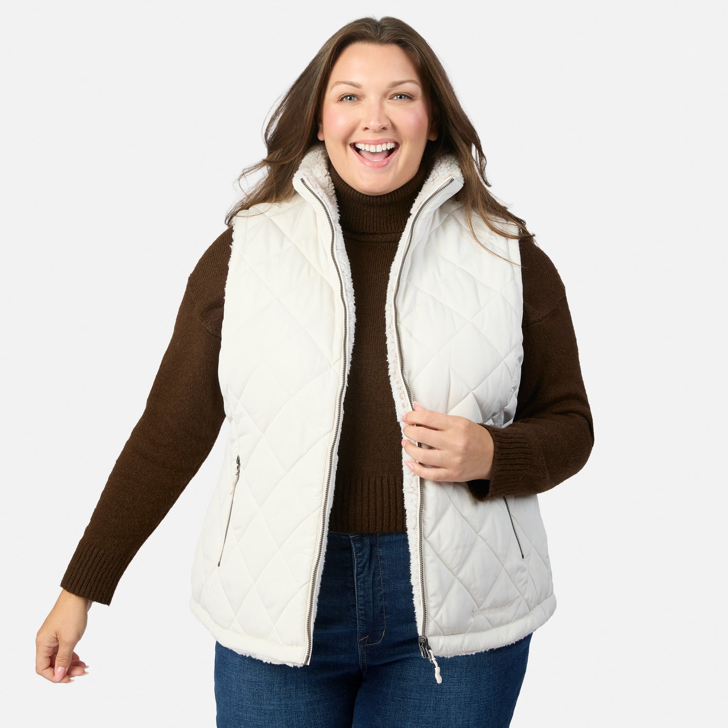 Smiling plus size woman wearing a white quilted Stratus Lite II reversible vest over a brown knit sweater.