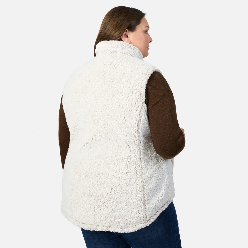 Profile of a woman wearing a white sherpa-lined Stratus Lite II reversible vest over a brown sweater with collar up.