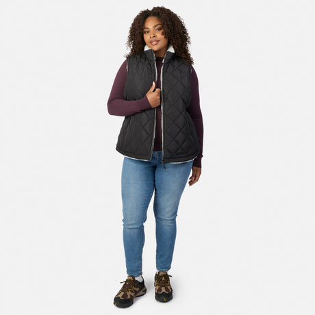 Front view of a woman in a black quilted Stratus Lite II reversible vest over a burgundy knit top and jeans