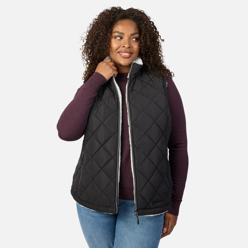 Plus size woman wearing black quilted vest with white fleece lining and zip closure over burgundy knit top.