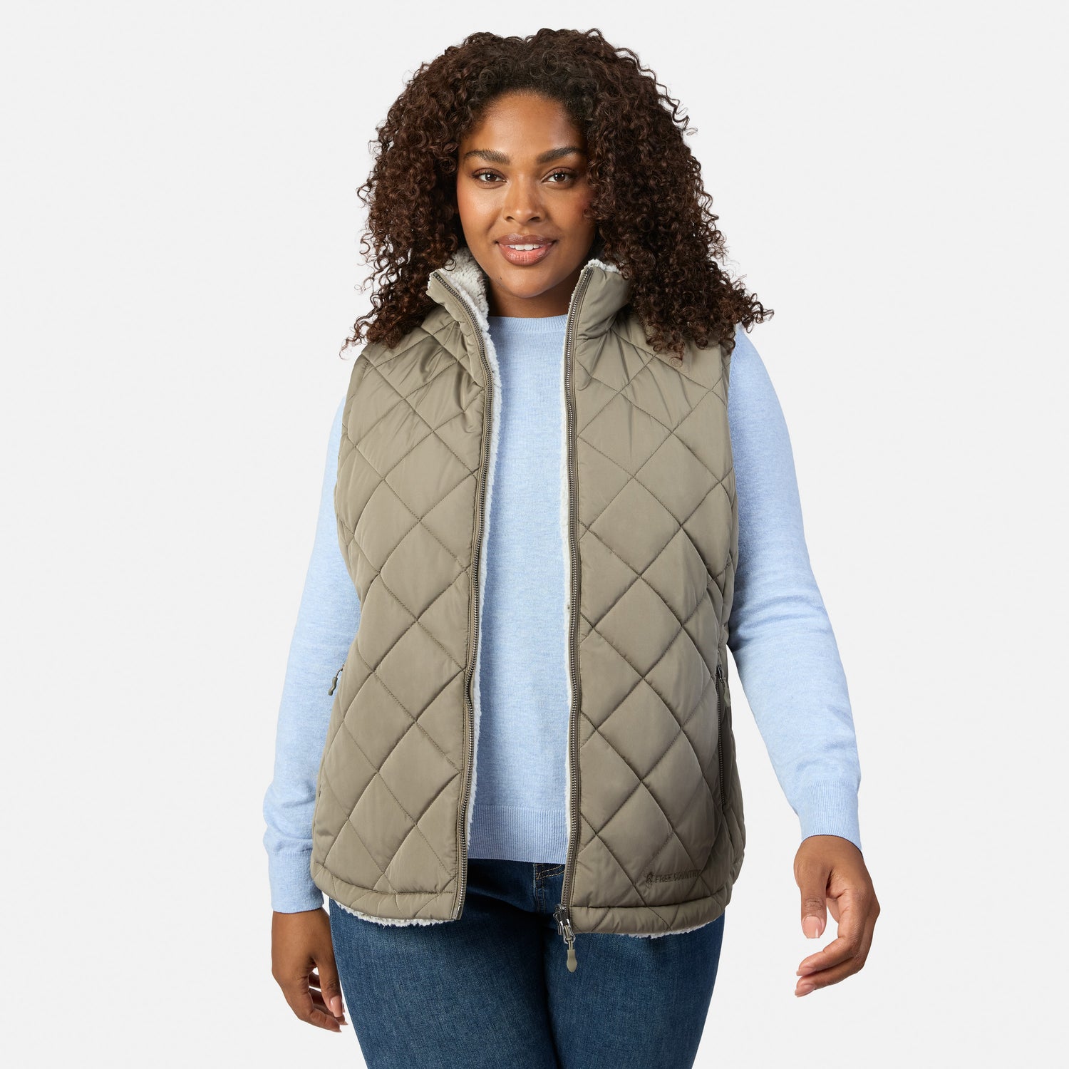 Plus-size woman wearing the reversible Stratus Lite II vest with white sherpa lining and olive exterior