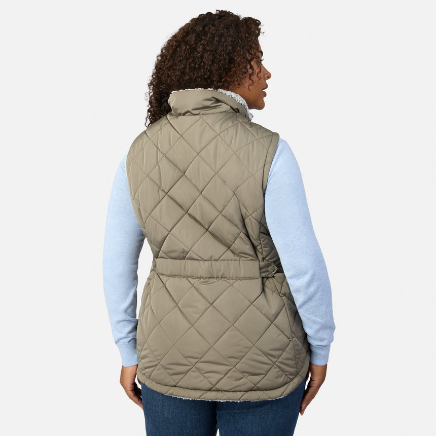 Back view of a woman wearing the taupe quilted Stratus Lite II Reversible Vest over a light blue sweater.
