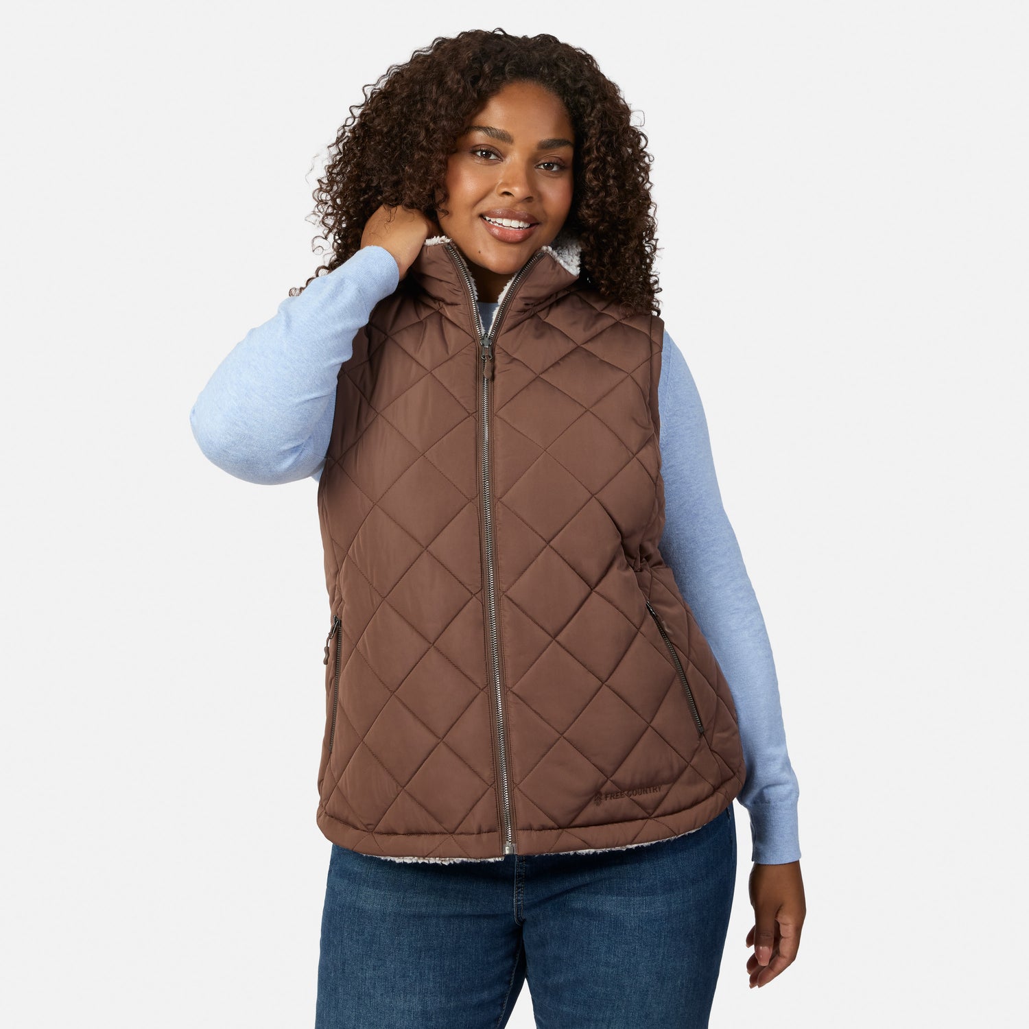 Woman in brown quilted reversible vest with sherpa lining worn over a blue knit top
