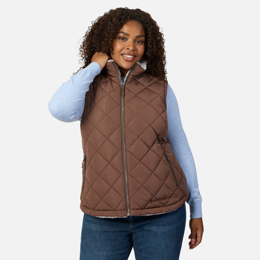 Woman in brown quilted reversible vest with sherpa lining worn over a blue knit top