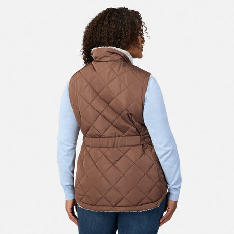 Back angled view of a plus-size woman in a brown quilted vest with sherpa lining over a light blue top.