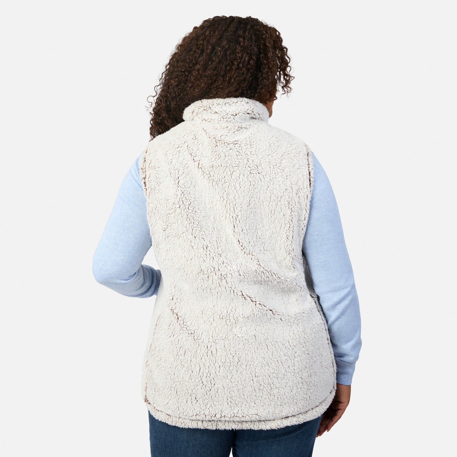 Back view of a plus-size woman wearing a tan quilted vest with white sherpa collar over a light blue long sleeve top.