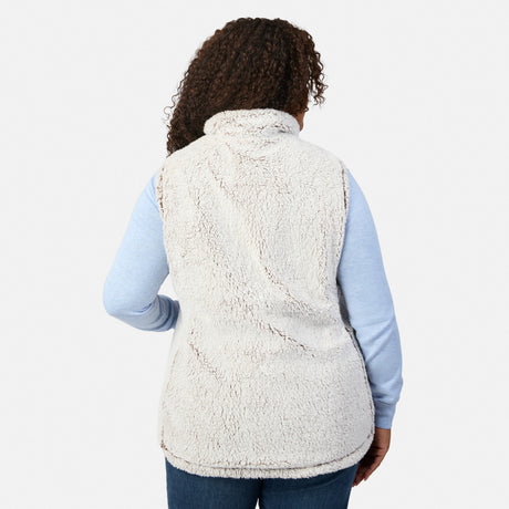 Back view of a plus-size woman wearing a tan quilted vest with white sherpa collar over a light blue long sleeve top.