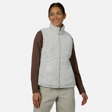 [Model is wearing size S.] A woman modeling a light gray sherpa fleece vest over a brown long-sleeve shirt and beige pants, photographed against a plain light gray studio background.