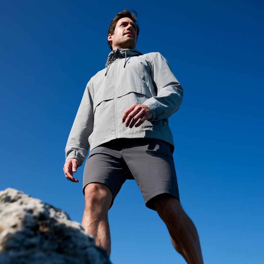 Man in athletic wear standing on a rock with a clear blue sky