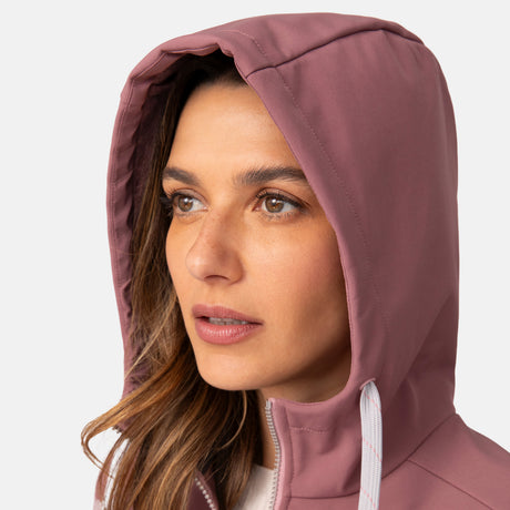 [Olga is 5’9” wearing a size Small.] Woman wearing Free Country Women's Alps Super Softshell® Jacket in pink with a full front zipper opening, soft lining, attached hood with adjustable drawcords, and water resistant and wind resistant stretch performance fabric, light grey background. Perfect women’s  jacket for fall weather.